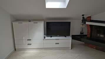 Una sala de estar moderna con un televisor de pantalla plana sobre un mueble blanco, una chimenea y un tragaluz.
