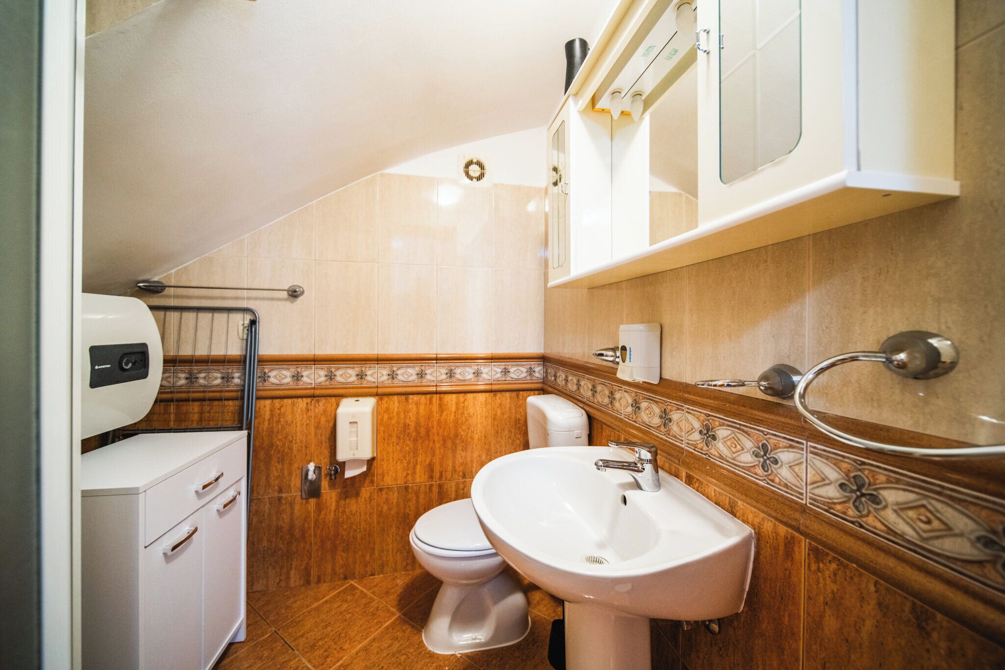 A bathroom with a toilet, sink, and cabinet.