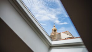 A view through a window of a building with a dome and a spire, under a clear sky. - M & J Central Suites (Korcula)