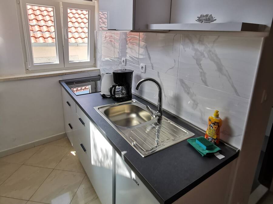 A modern kitchen with a stainless steel sink, a coffee maker, and a bottle of dish soap.