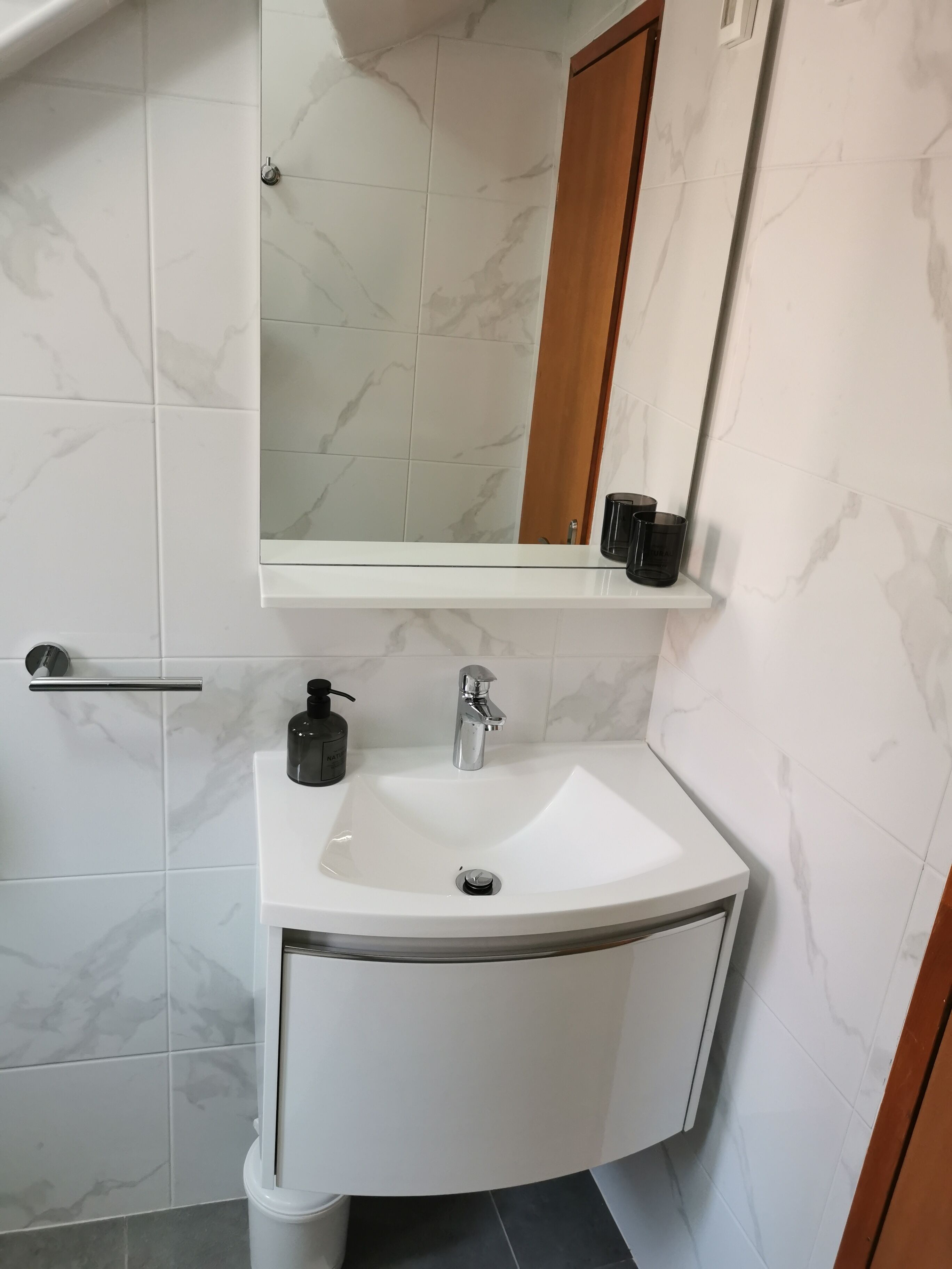 A bathroom with a white sink, a mirror, and a soap dispenser.