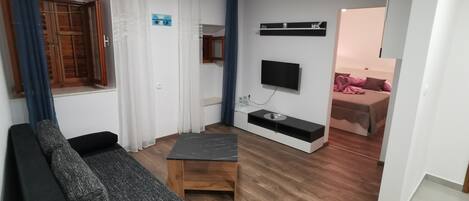 Una sala de estar moderna con un sofá, una mesita de centro y un televisor montado en la pared.