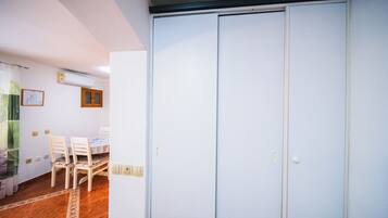 Una habitación con un armario blanco, una mesa de comedor con sillas y una ventana con cortinas.