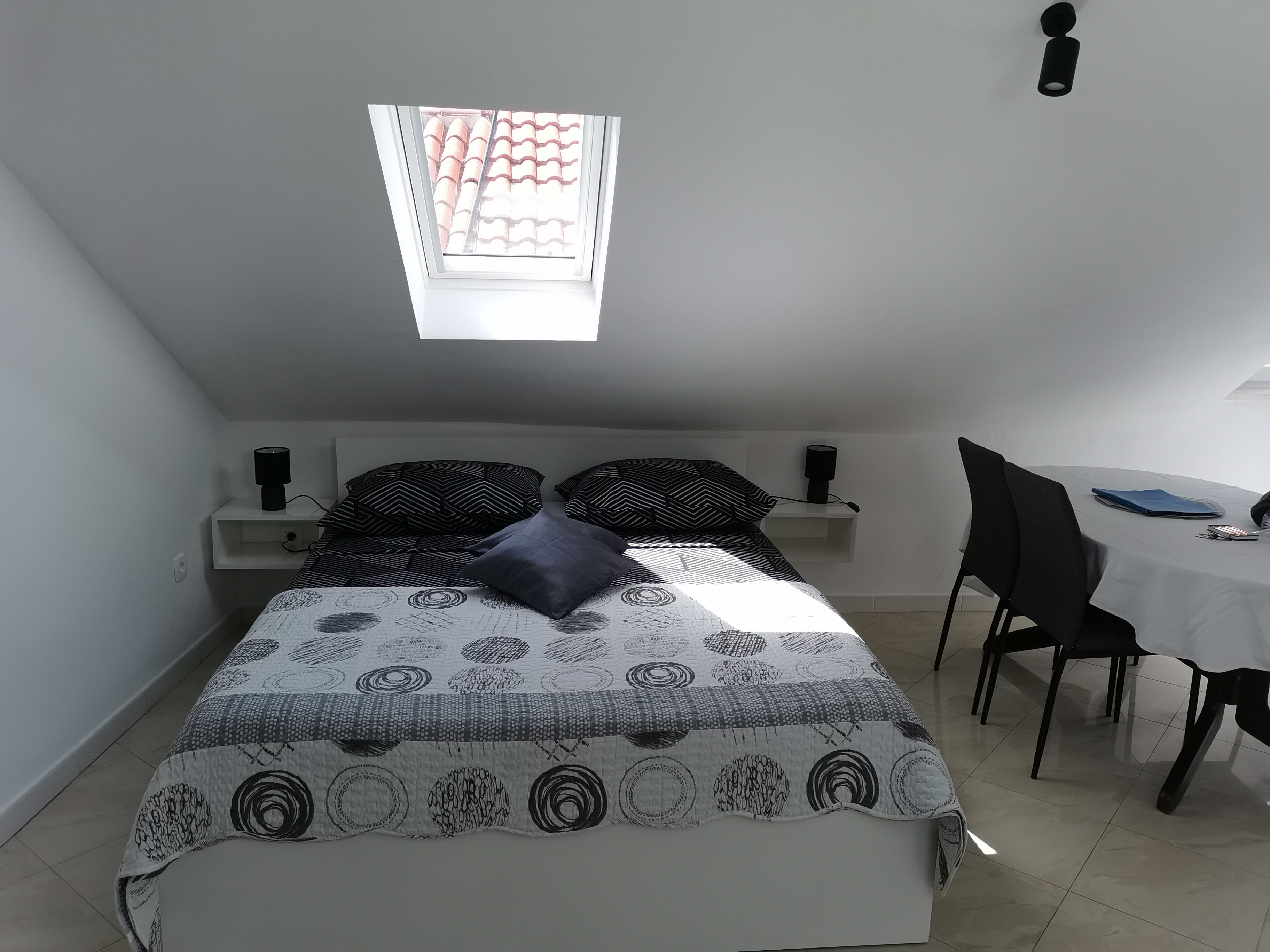A bedroom with a bed, bedside tables, a desk, and a chair.