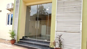 A building entrance with a glass door, steps, and potted plants. - Alexia's Place Hotel (Lagos)
