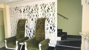 A lobby with two green armchairs, a white decorative wall, and a staircase. - Alexia's Place Hotel (Lagos)