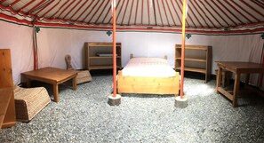 A traditional yurt with a central bed, wooden benches, and shelves. - Yourtes de Montagnes Insolites (Val-Cenis)