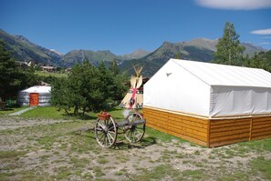 A yurt with a white canvas roof, a wooden base, and a wooden wagon nearby. - Yourtes de Montagnes Insolites (Val-Cenis)