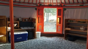 A cozy room with a wooden interior, a red door, and a view of the outdoors. - Yourtes de Montagnes Insolites (Val-Cenis)