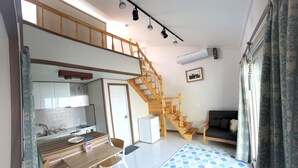 A compact living space with a kitchen, dining area, and a staircase leading to an upper level. - Daisy (Jeju City)