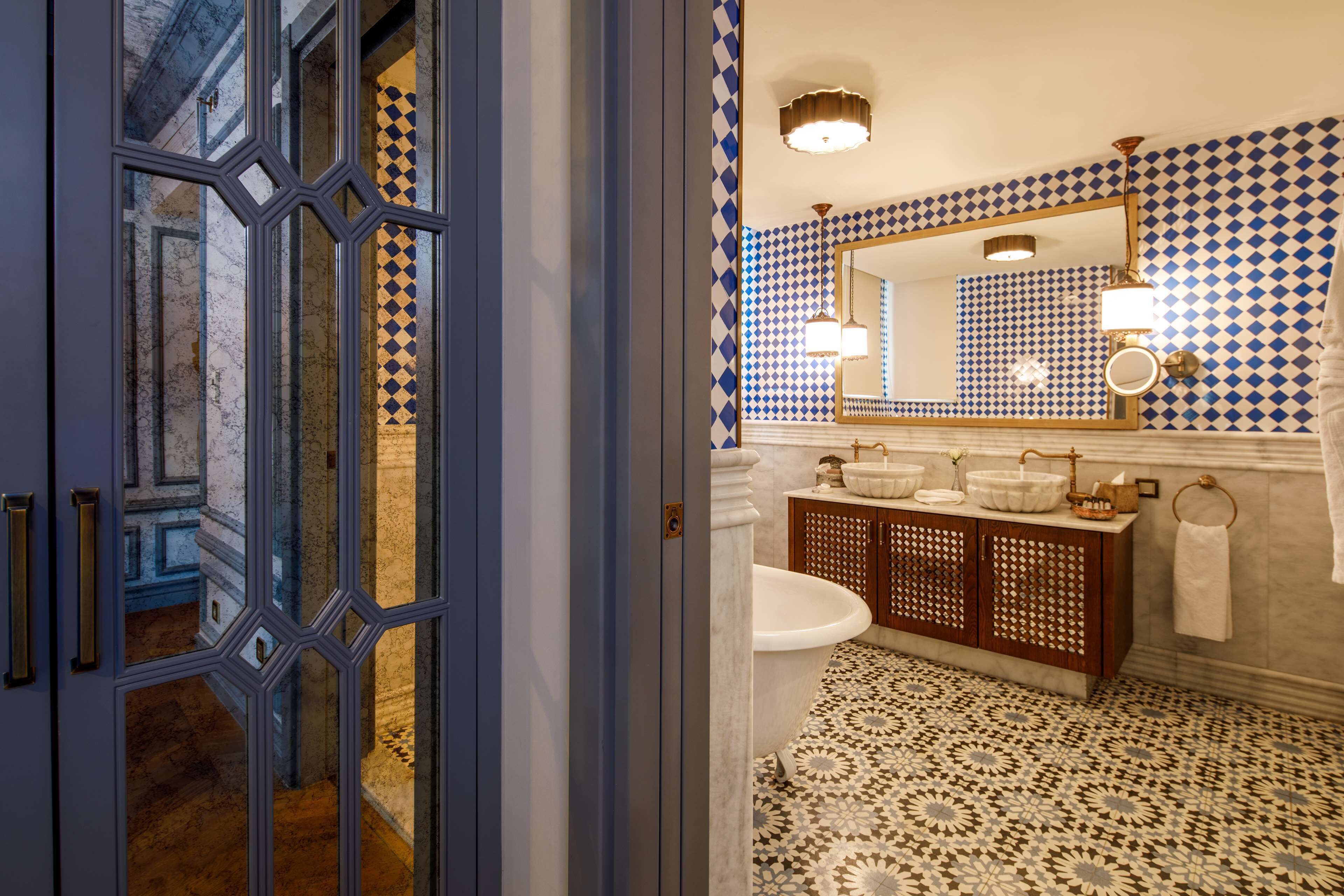 A bathroom with a white bathtub, a wooden vanity, and a patterned floor.