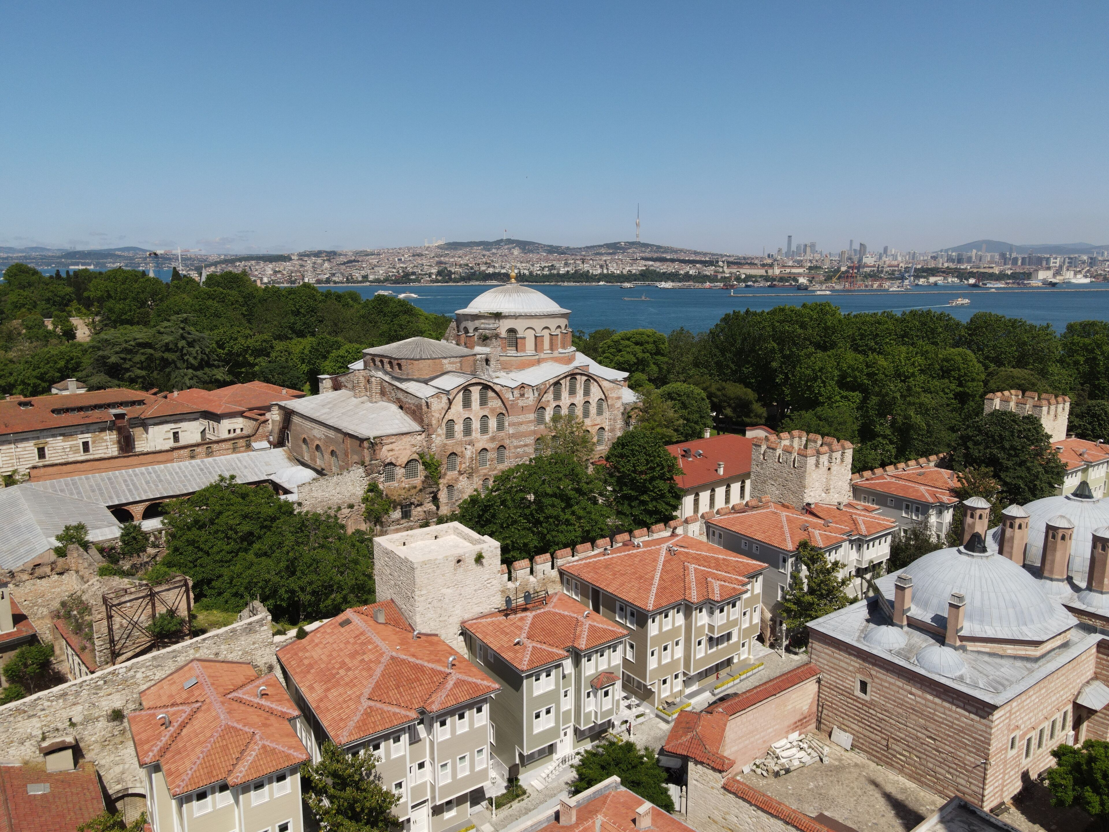 A historic building with a large dome, surrounded by traditional architecture and a view of a body of water.
