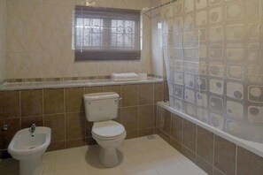 A bathroom with a toilet, bidet, and shower curtain. - Perfect Havens at Noah's Court (Lekki)