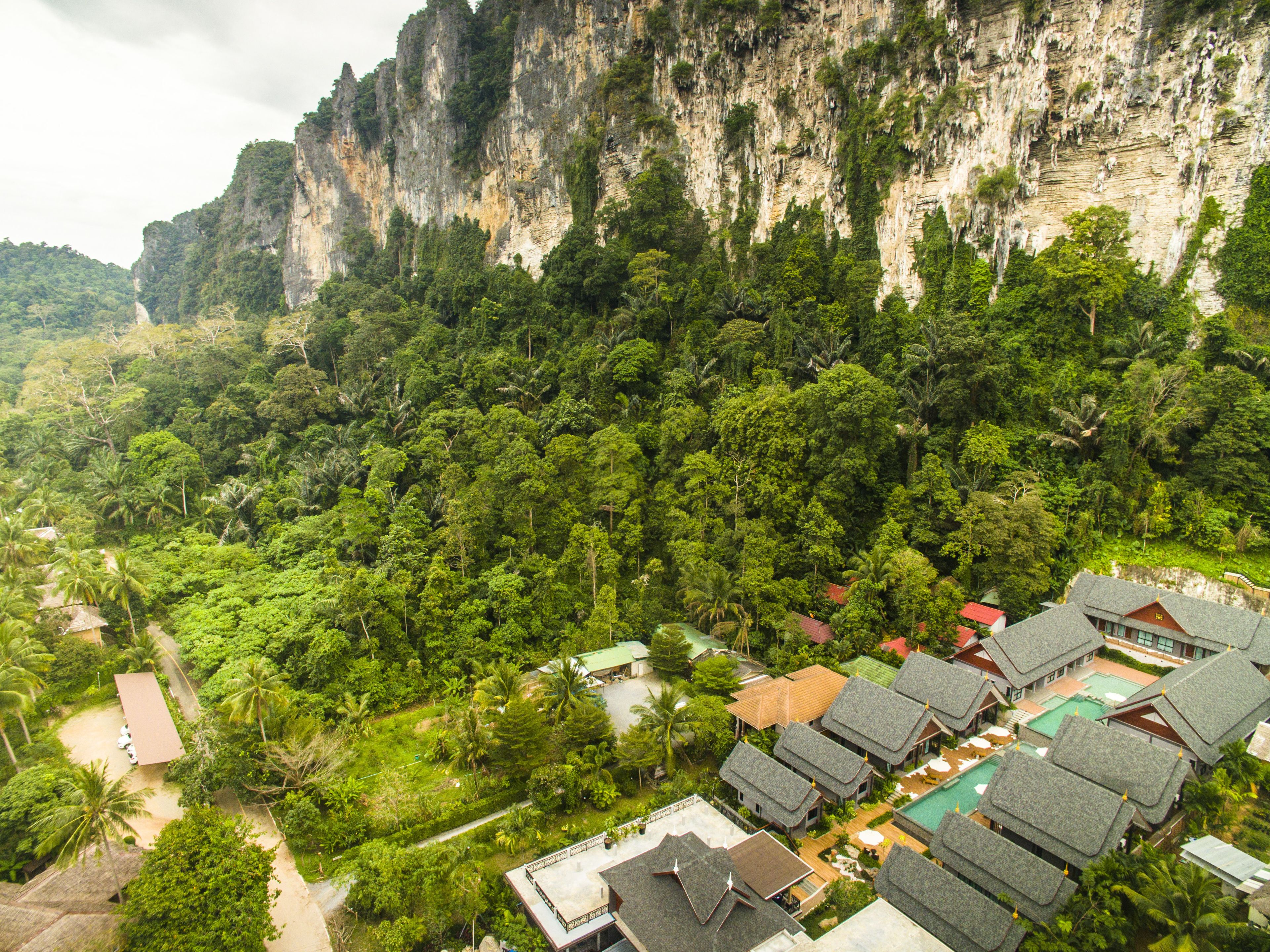 Un complexe hôtelier doté d’une architecture traditionnelle, d’une végétation luxuriante et situé au pied d’une falaise.