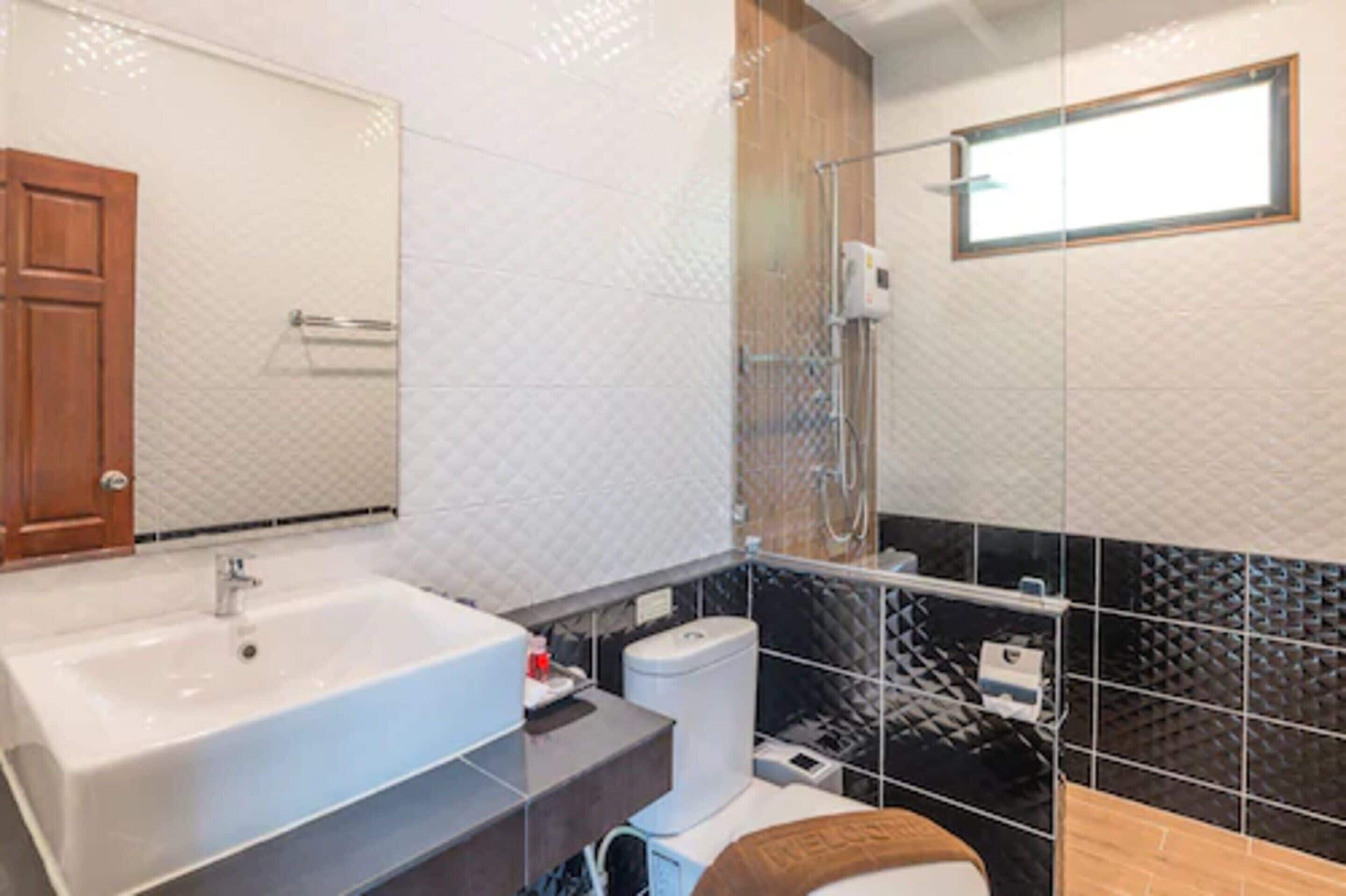 A modern bathroom with a large sink, toilet, and shower area.