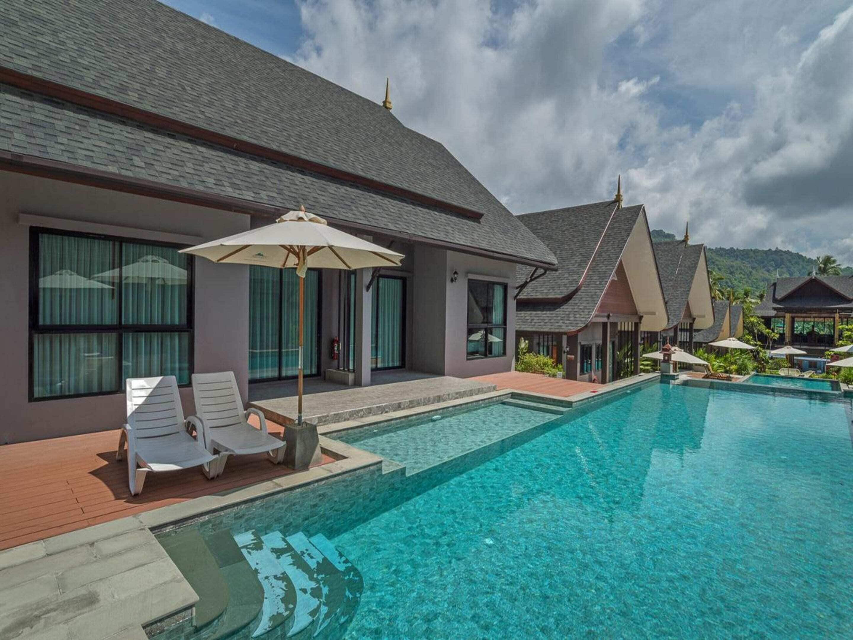 A modern resort with a swimming pool, lounge chairs, and umbrellas.