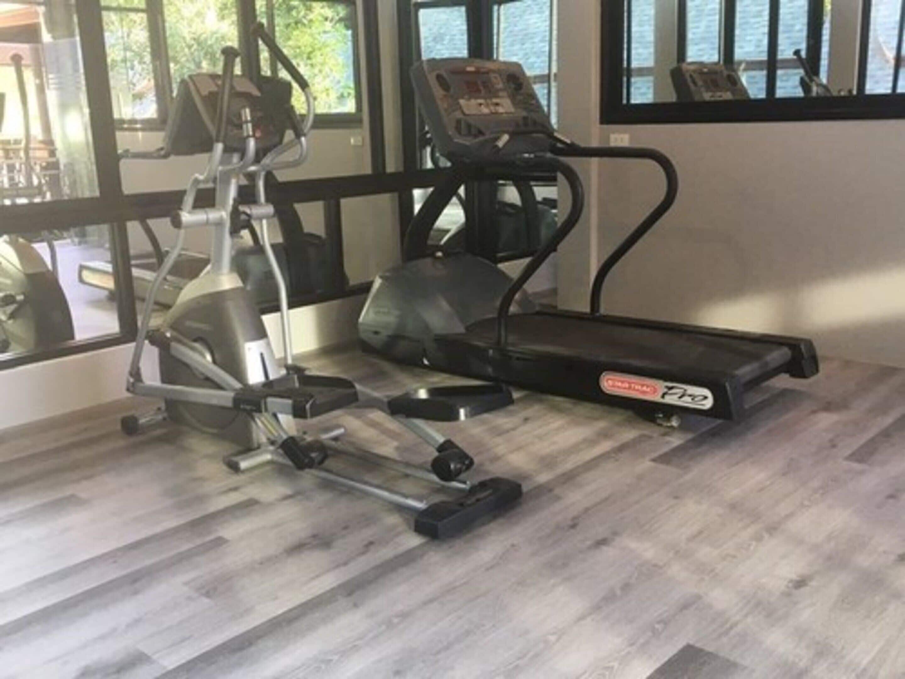 A gym with cardio equipment including a treadmill and elliptical machine.