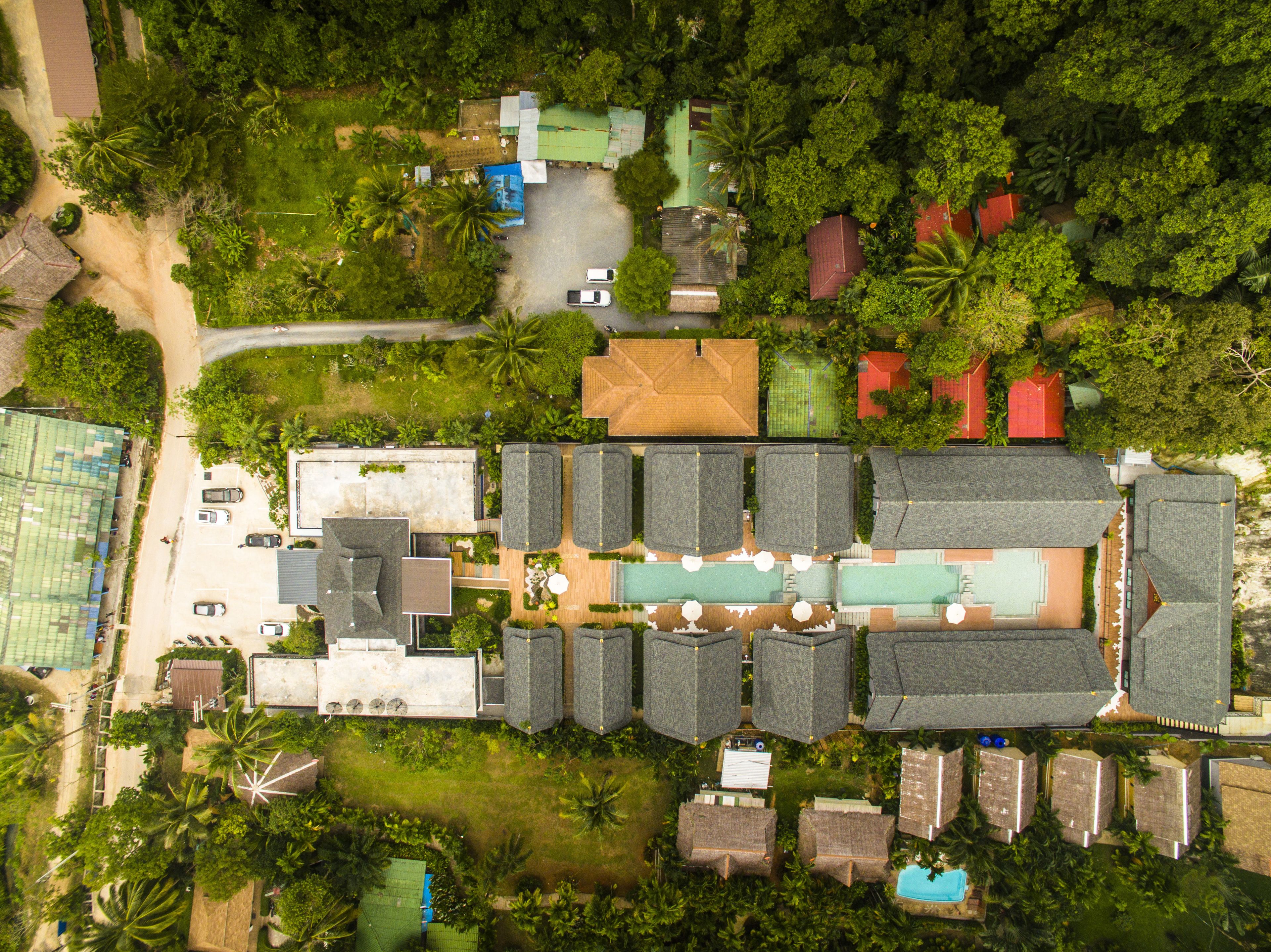 An aerial view of a resort with multiple buildings, a swimming pool, and lush greenery.