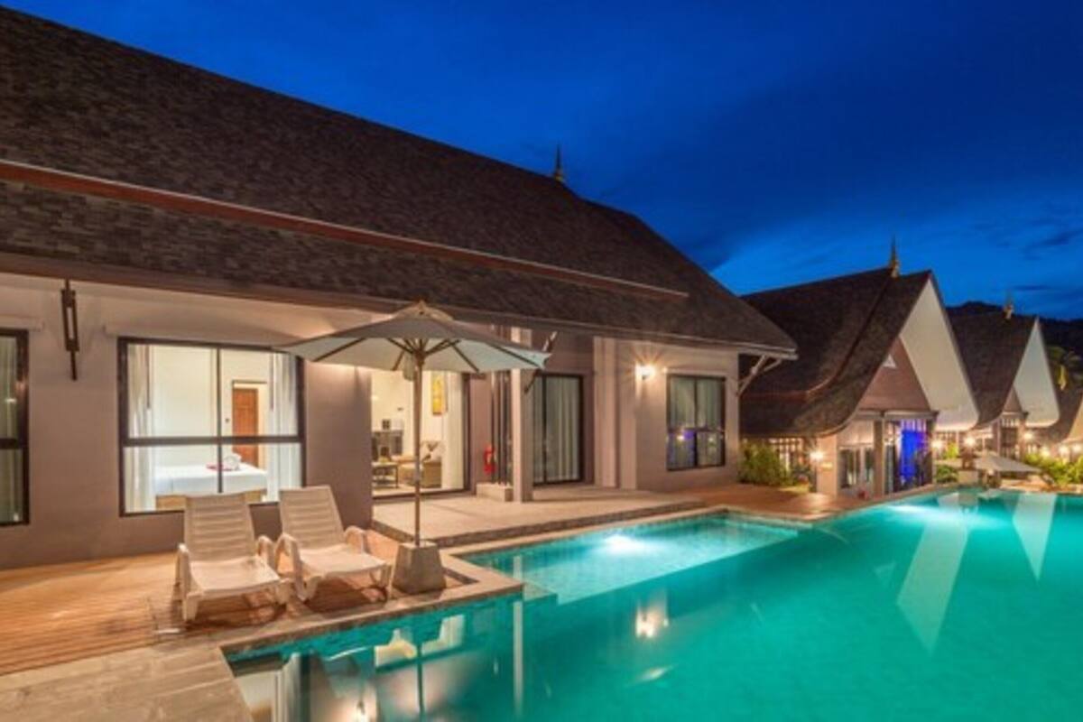 A modern resort with a swimming pool, lounge chairs, and a covered outdoor area.