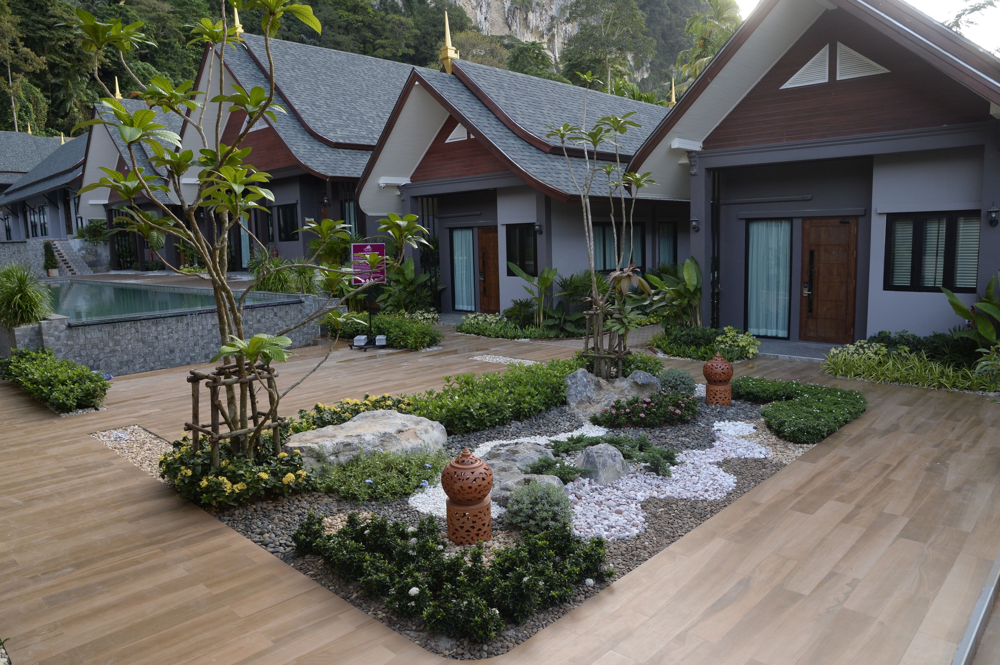 Un complexe hôtelier doté d’une piscine, d’une terrasse en bois et d’un jardin bien entretenu.