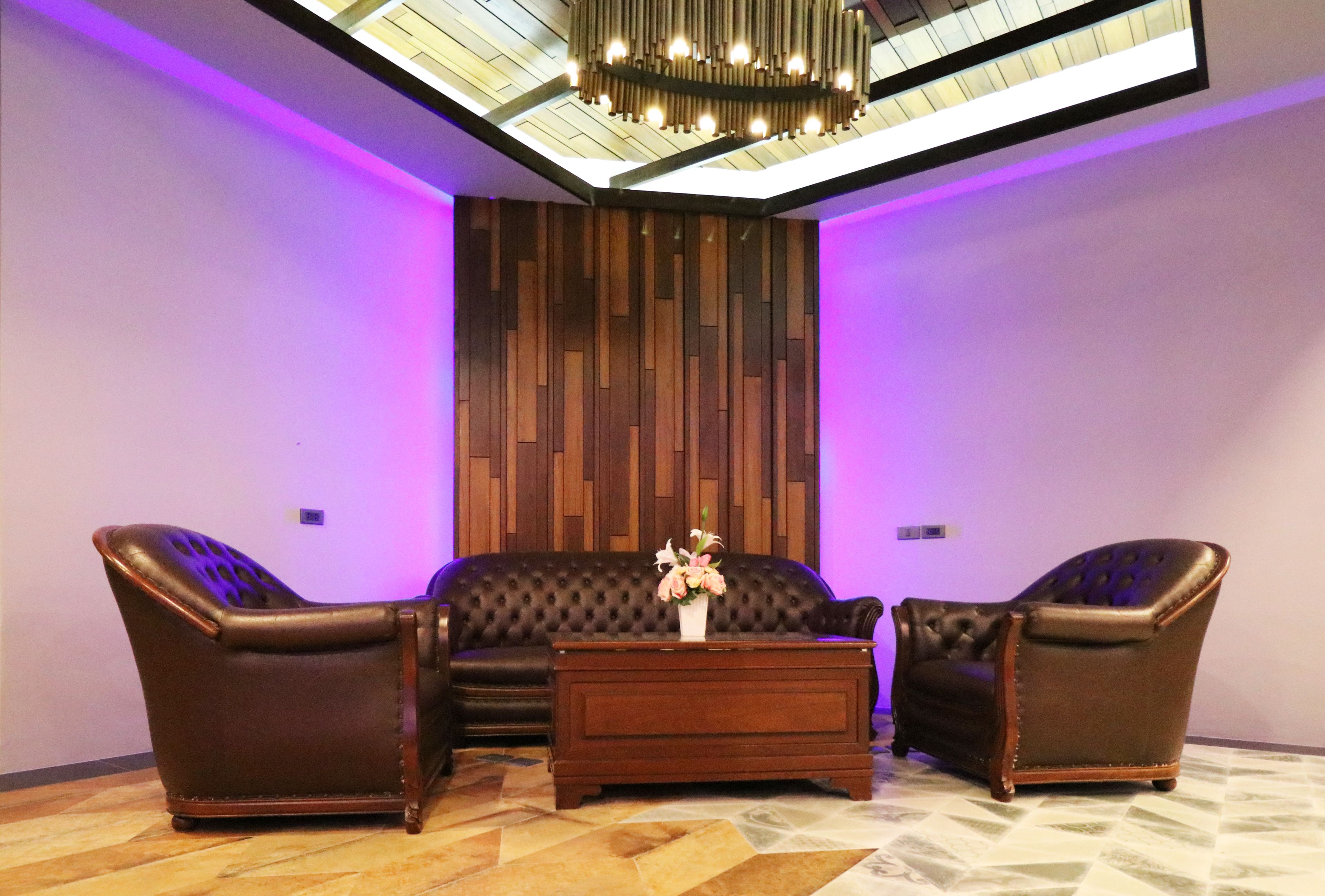Una sala de estar moderna con un sofá de cuero marrón oscuro, dos sillones a juego y una mesa de centro de madera.
