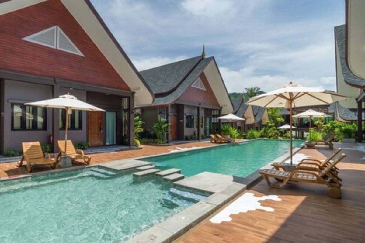 A modern resort with a swimming pool, lounge chairs, and umbrellas.
