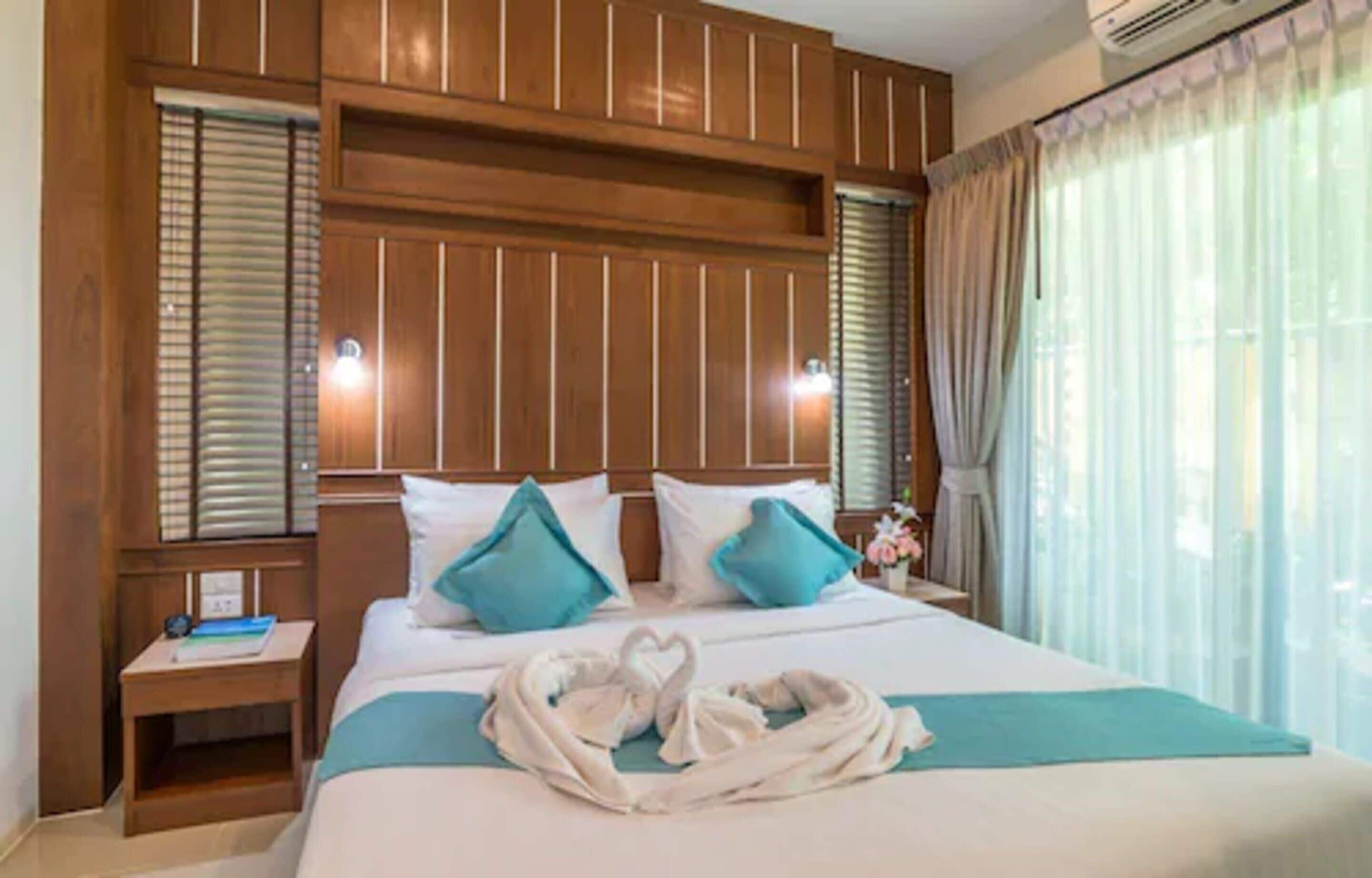 Habitación de hotel con una cama grande, dos mesitas de noche y cabecera con iluminación integrada.
