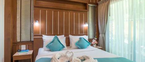 A hotel room with a large bed, two bedside tables, and a headboard with built-in lighting.