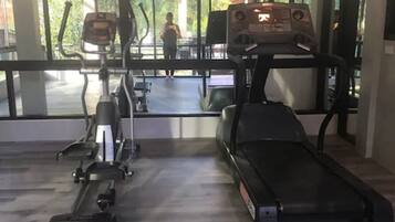 Un gimnasio con equipo de cardio, incluyendo una cinta de correr y una máquina elíptica.