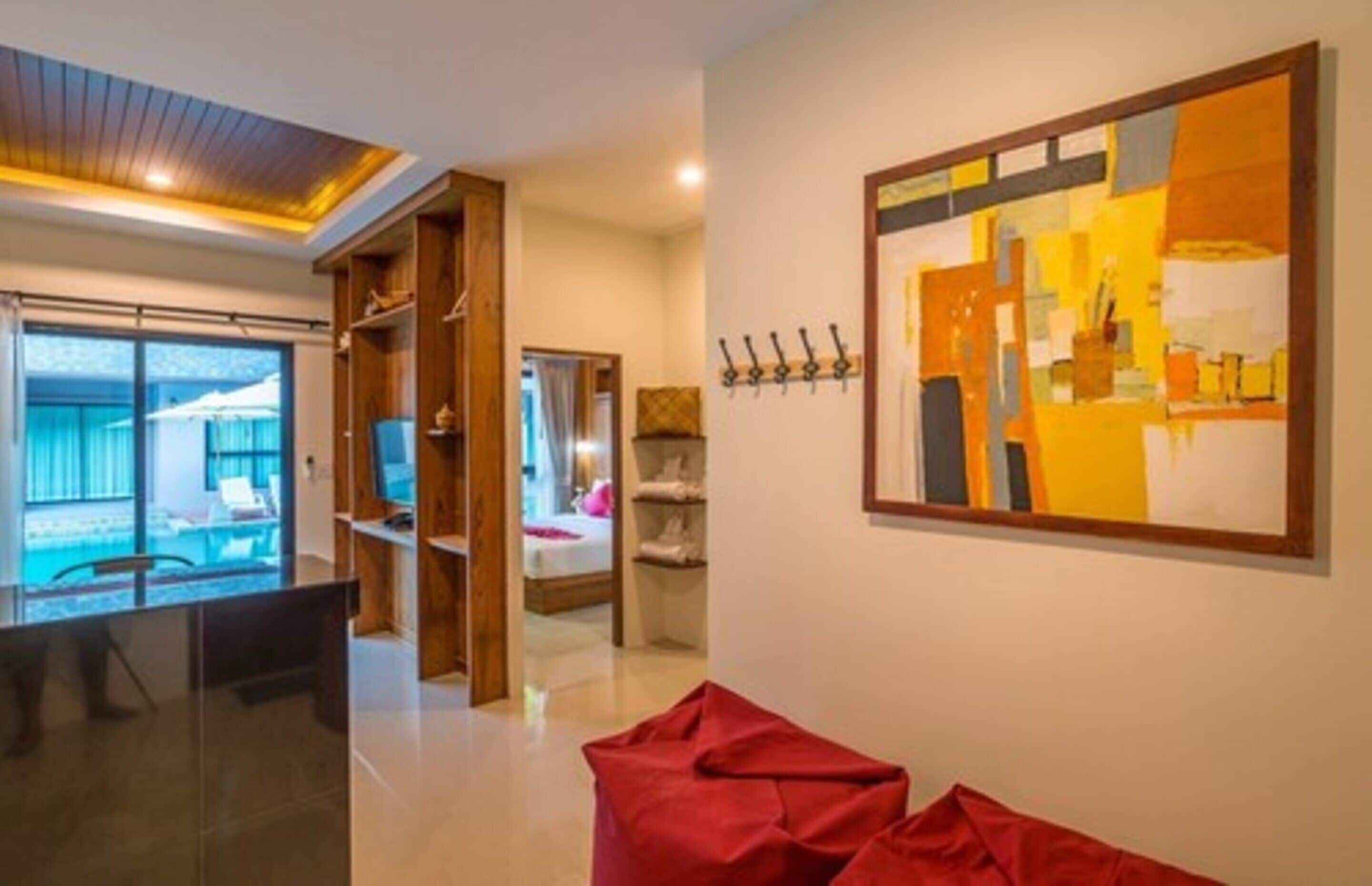 A modern hotel room with a balcony, a large abstract painting, and a wooden wardrobe.