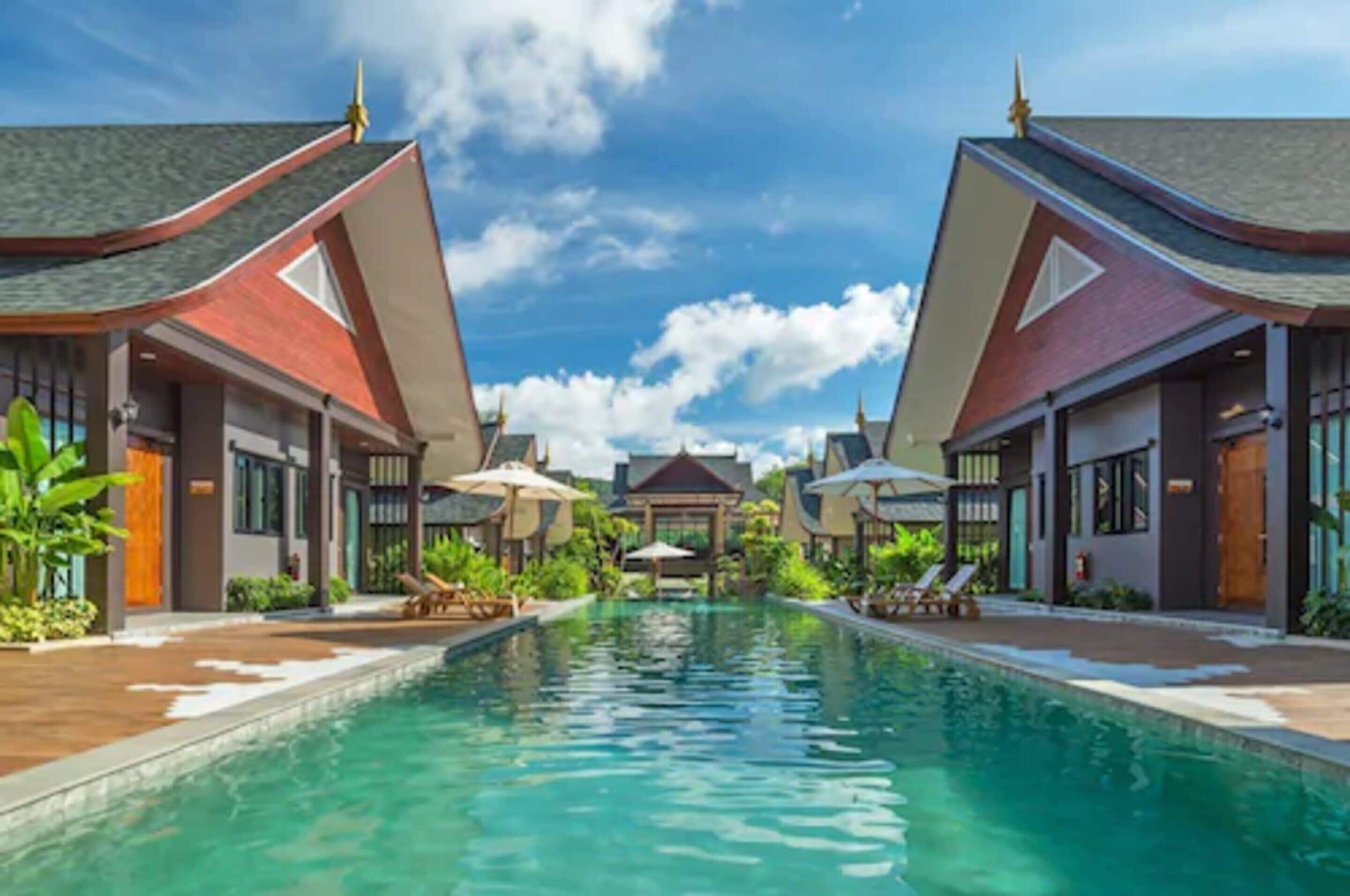 A resort with a central pool, two-story buildings with red roofs, and a gazebo in the background.