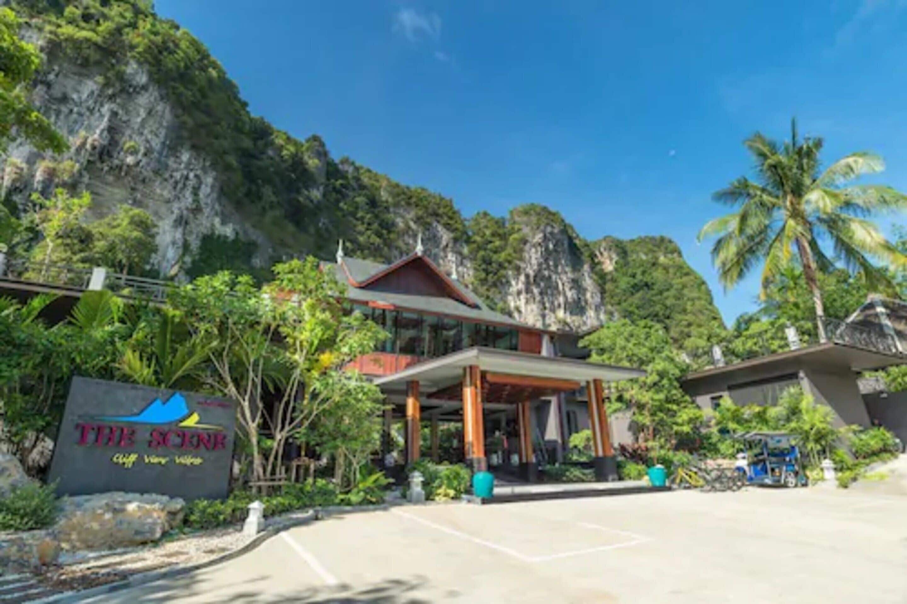 Un hotel llamado 'The Scene' con un diseño arquitectónico moderno, ubicado en una zona montañosa exuberante bajo un cielo despejado.
