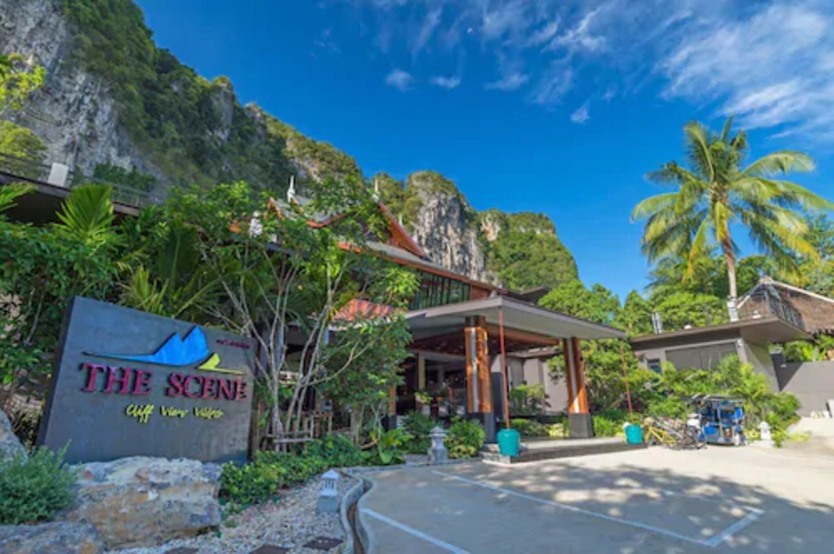 Un hotel llamado "The Scene" con vista a un acantilado, rodeado de exuberante vegetación y un paisaje montañoso.
