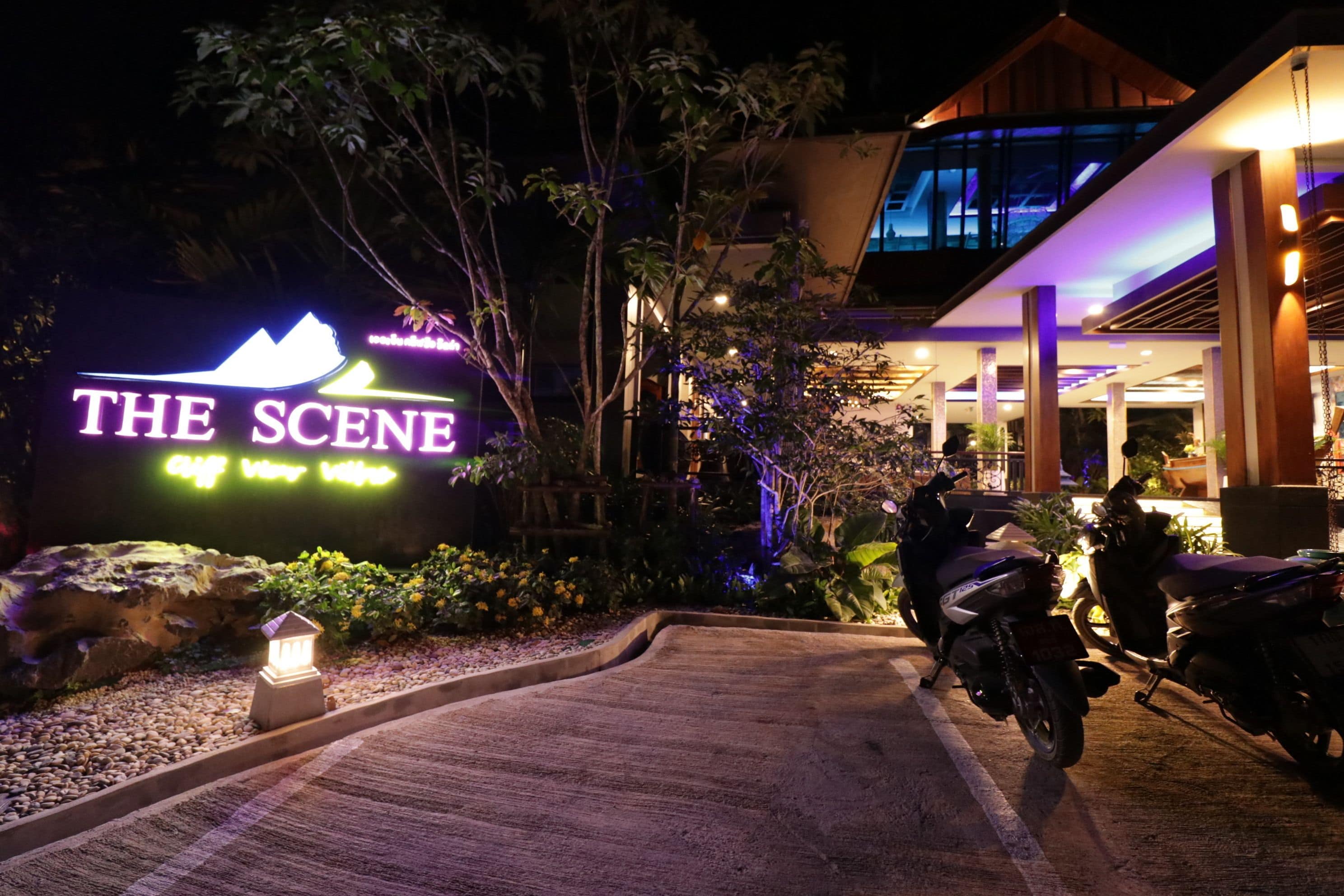 A hotel entrance with a neon sign reading "THE SCENE."
