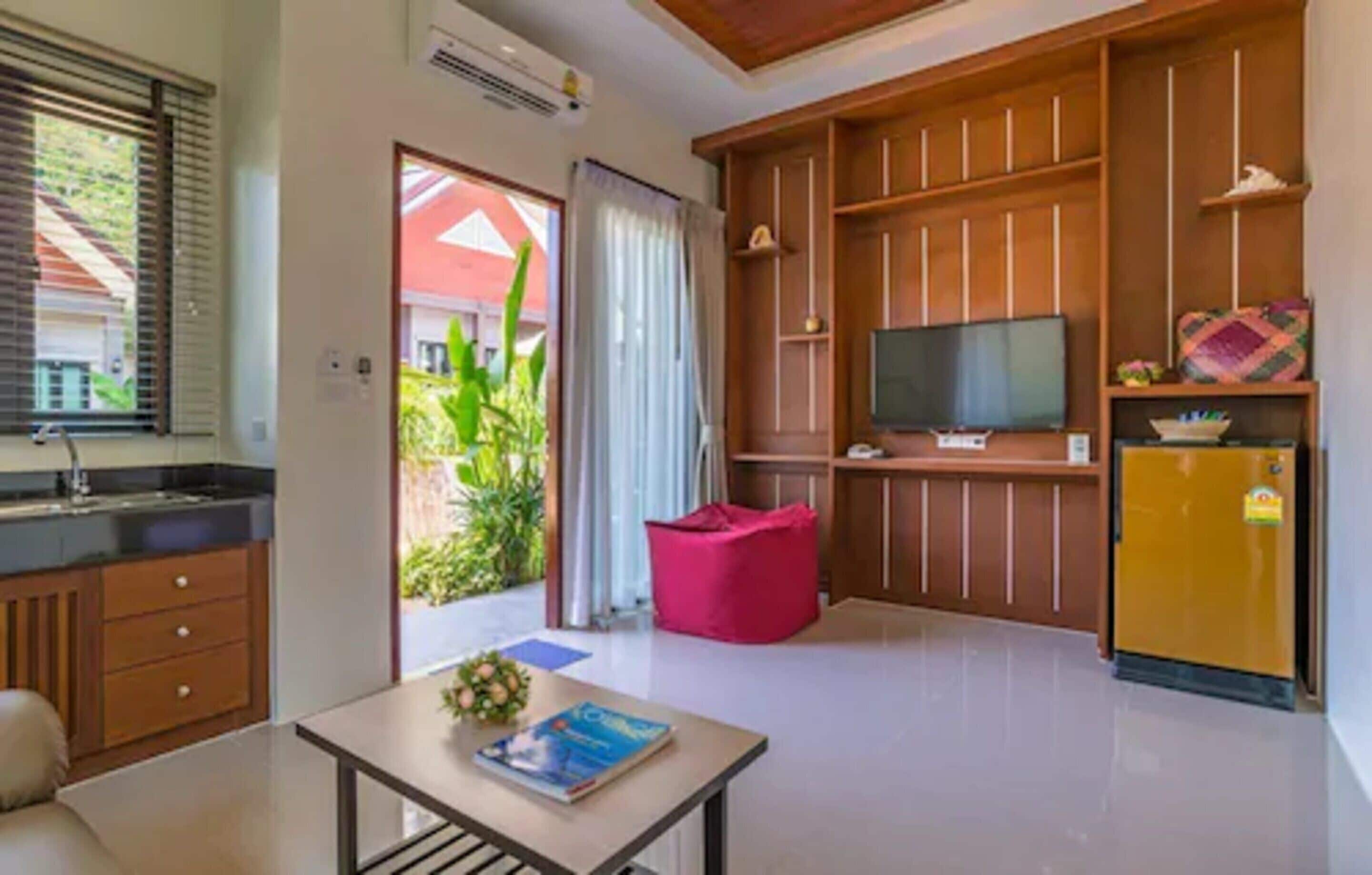 Una sala moderna con área de cocina, televisor y refrigerador.