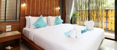 A hotel room with a large bed, wooden headboard, and a view of bamboo outside.