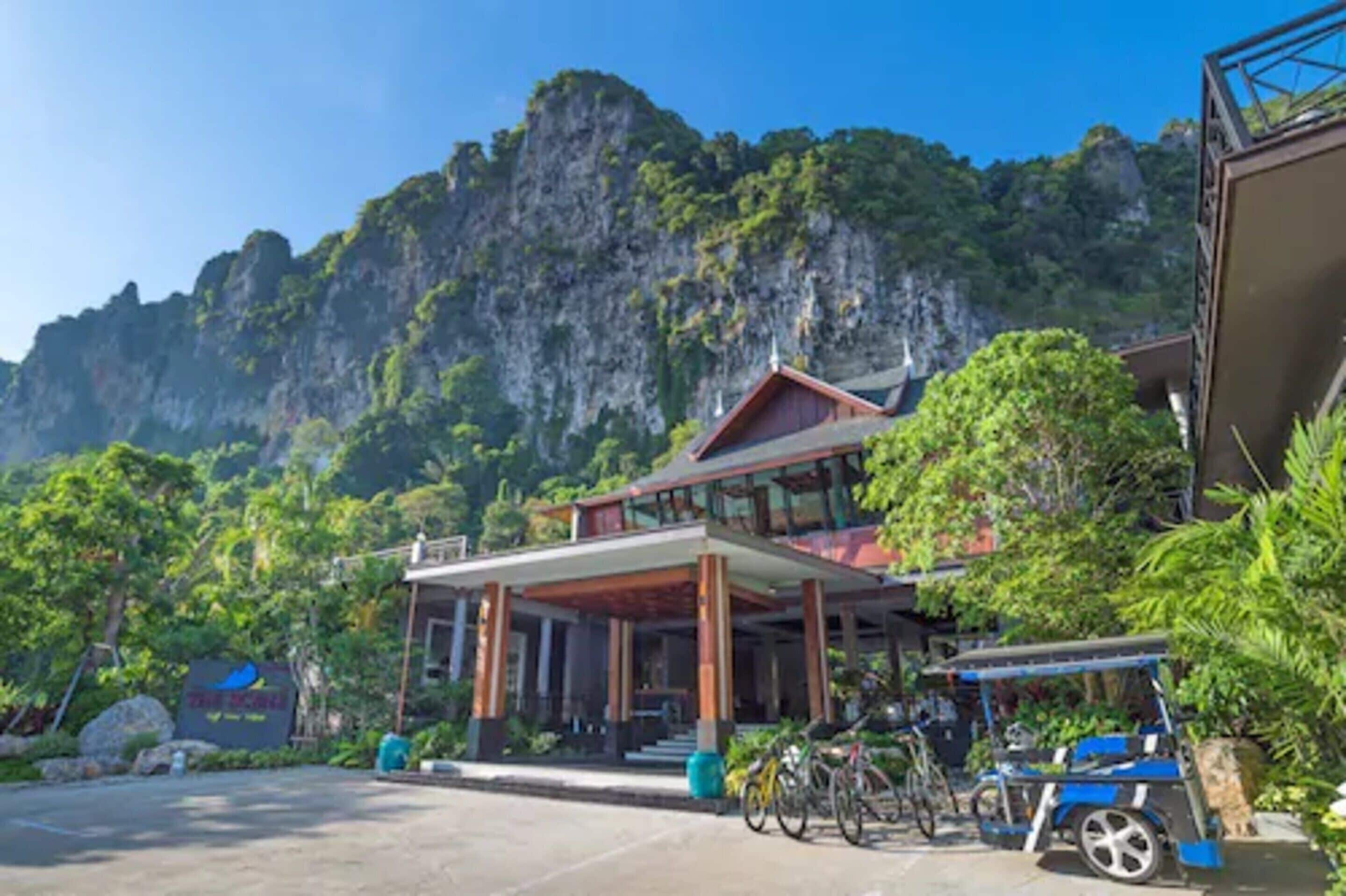 A resort with a large building surrounded by lush greenery and a mountainous backdrop.