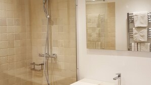 A modern bathroom with a glass-enclosed shower, a large mirror, and a vanity with a sink and towel rack. - Hotel Le Relais Du Postillon (Antibes)