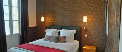 Una habitación de hotel con cama, mesita de noche y pared con diseño.