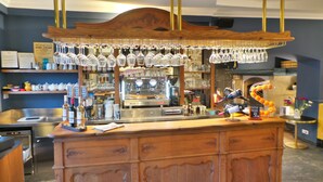 A bar area with a wooden counter, a coffee machine, and a wine cooler. - Hotel Le Relais Du Postillon (Antibes)