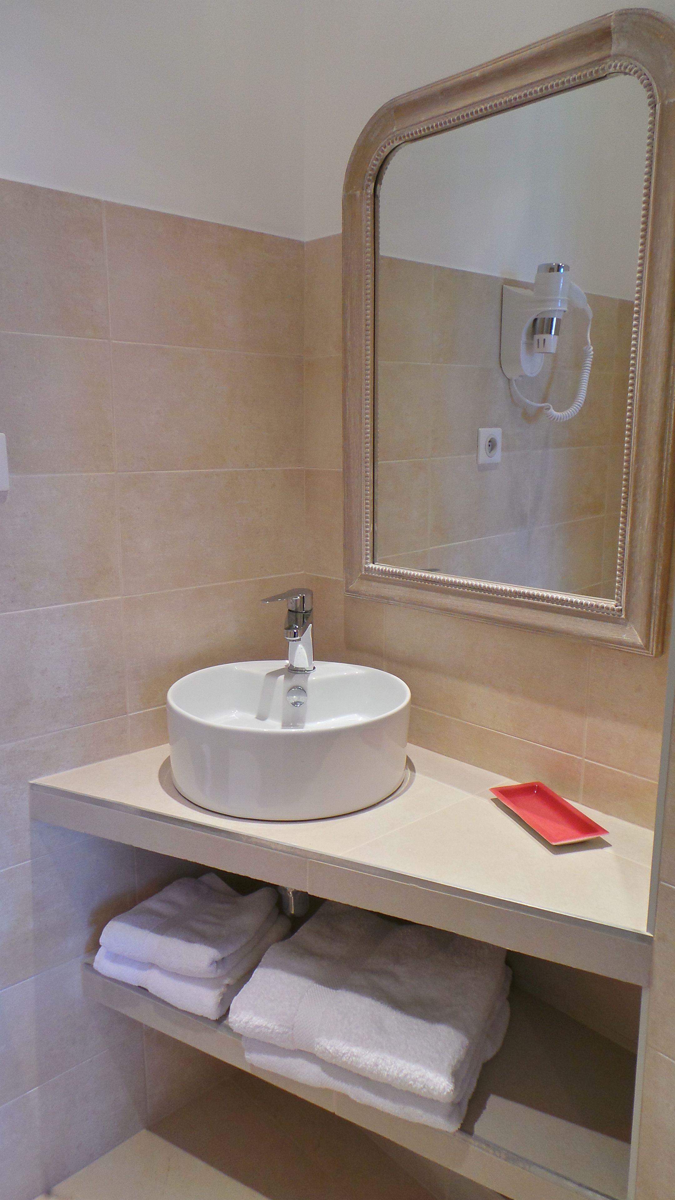 Une salle de bain avec un lavabo blanc, un miroir et un porte-serviettes.