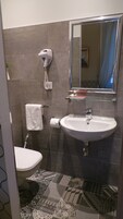 A bathroom with a toilet, sink, and hand dryer.
