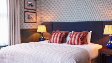 A neatly made bed with a striped pillow and a blue lamp beside it.