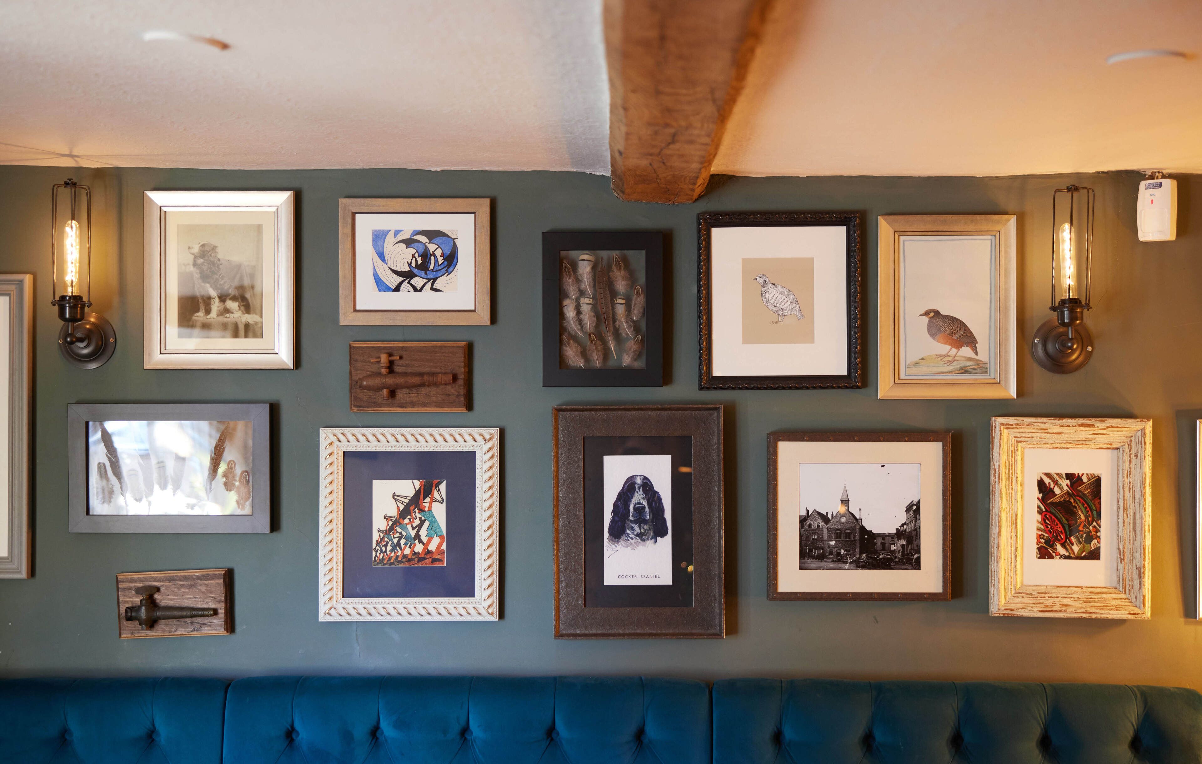 Een muur met diverse ingelijste foto's en wandlampen.