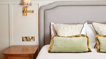 A neatly made bed with patterned pillows, a bedside table with drawers, and a wall-mounted lamp.