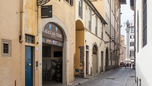 Une rue étroite avec un bâtiment sur lequel on peut voir une enseigne indiquant « GARAGE delle TERME » et une porte bleue.