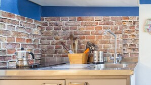 Une cuisine avec un mur de fond en briques, des appareils électroménagers en acier inoxydable et des armoires en bois.