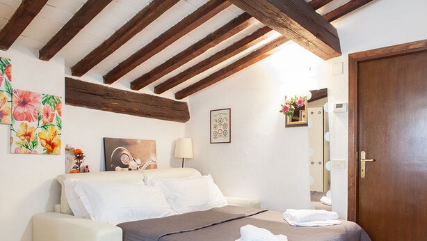 Une chambre à coucher avec un lit, une table de chevet, une lampe, un miroir et une porte.