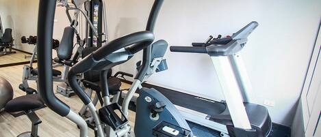 A gym with cardio machines, a treadmill, and weightlifting equipment.