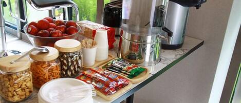 A breakfast buffet setup with various food items, a coffee maker, and a kettle on a marble countertop.